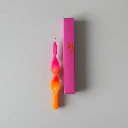 Zwei gedrehte Kerzen in Pink und Orange, eine in einer pinken Verpackung