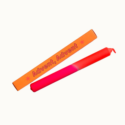 Eine kräftige Neon-Pink und Neon-Orange getauchte Stabkerze von Pink Stories im Dip-Dye-Look, mit der passenden orangen Geschenkbox und der Aufschrift „Advent, Advent