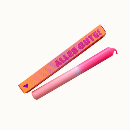 Freigestellte Pink Stories Dip-Dye Stabkerze in Neon Pink und Rosa mit ALLES GUTE! Verpackung auf weißem Hintergrund