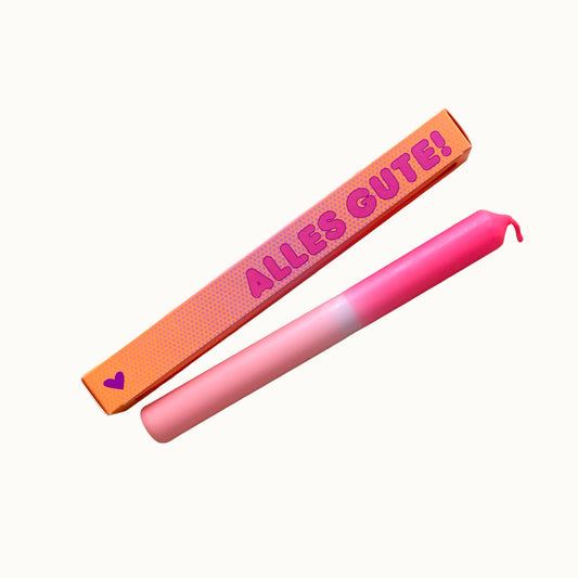 Freigestellte Pink Stories Dip-Dye Stabkerze in Neon Pink und Rosa mit ALLES GUTE! Verpackung auf weißem Hintergrund