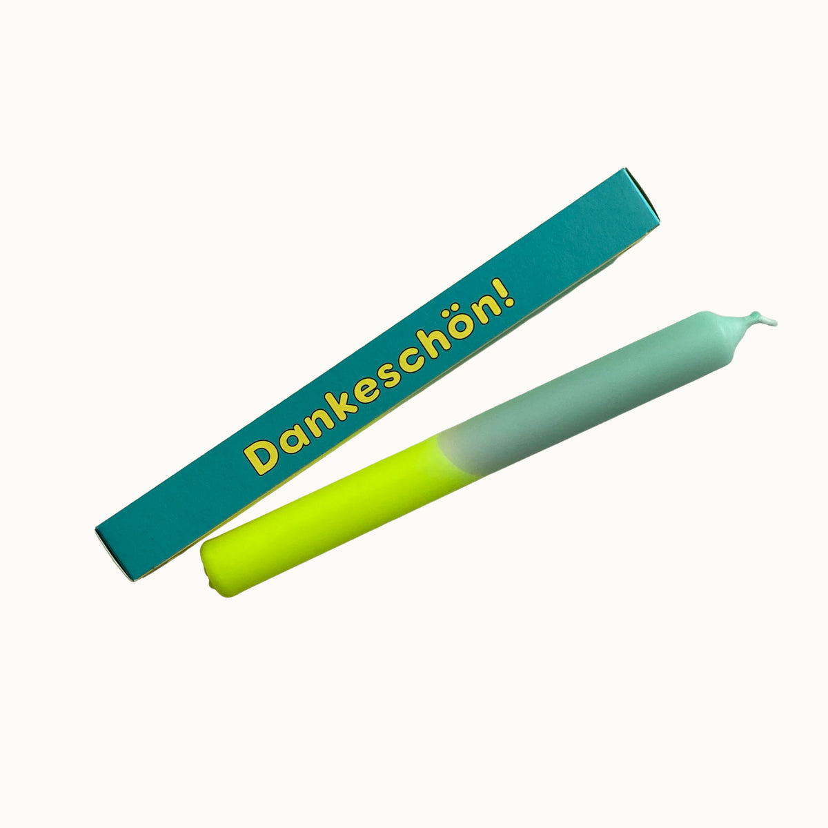 Eine Dip-Dye-Stabkerze mit Farbverlauf von Lime-Gelb zu Pastellgrün von Pink Stories, abgebildet mit ihrer türkisfarbenen Geschenkbox und der Aufschrift „Dankeschön!“.