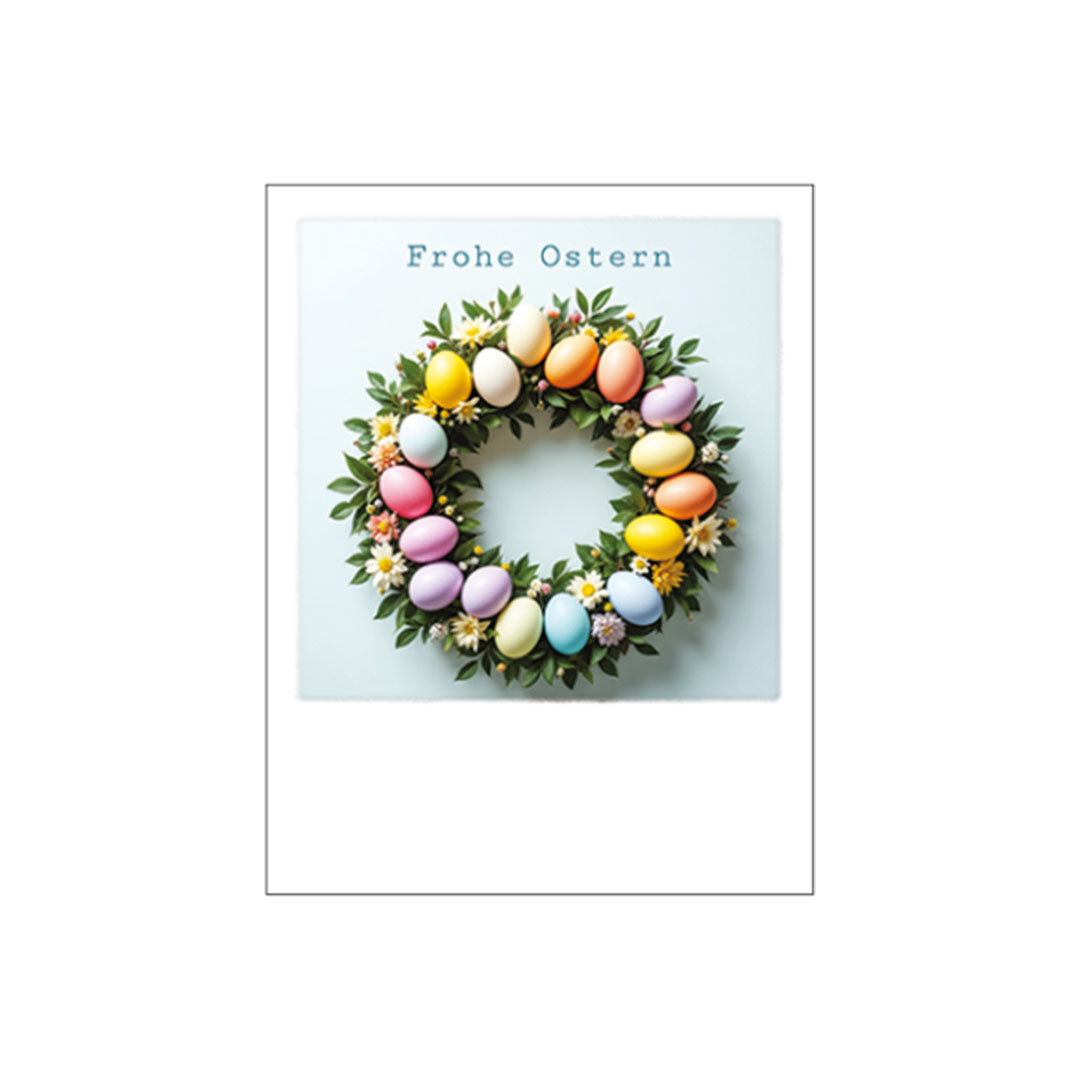 Ein runder Kranz aus grünen Blättern und kleinen weißen Blüten, geschmückt mit farbenfrohen Ostereiern in Pastelltönen. Über dem Kranz steht der Schriftzug „Frohe Ostern“.