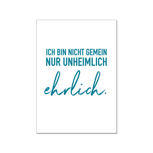 Postkarte im Hochformat mit weißem Hintergrund. Der Text in Petrolblau lautet: „ICH BIN NICHT GEMEIN NUR UNHEIMLICH ehrlich.“, wobei das Wort „ehrlich“ in einer eleganten Schreibschrift hervorgehoben ist.