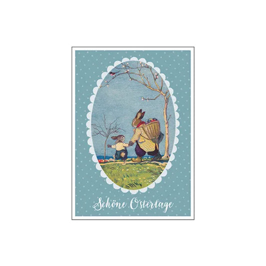 Eine nostalgische Osterkarte im Vintage-Stil. Ein großer und ein kleiner Hase wandern an einer Küste entlang; der große Hase trägt einen Korb voller bunter Ostereier auf dem Rücken. Text unten: „Schöne Ostertage