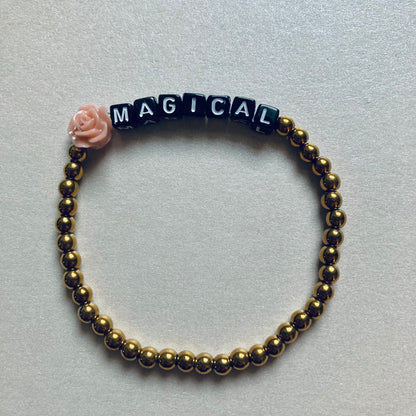 Minimalistisches Armband mit weißen Buchstaben-Perlen auf schwarzem Grund, Wortlaut MAGICAL, Länge 17,5 cm.