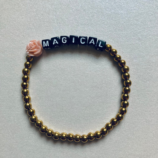 Minimalistisches Armband mit weißen Buchstaben-Perlen auf schwarzem Grund, Wortlaut MAGICAL, Länge 17,5 cm.