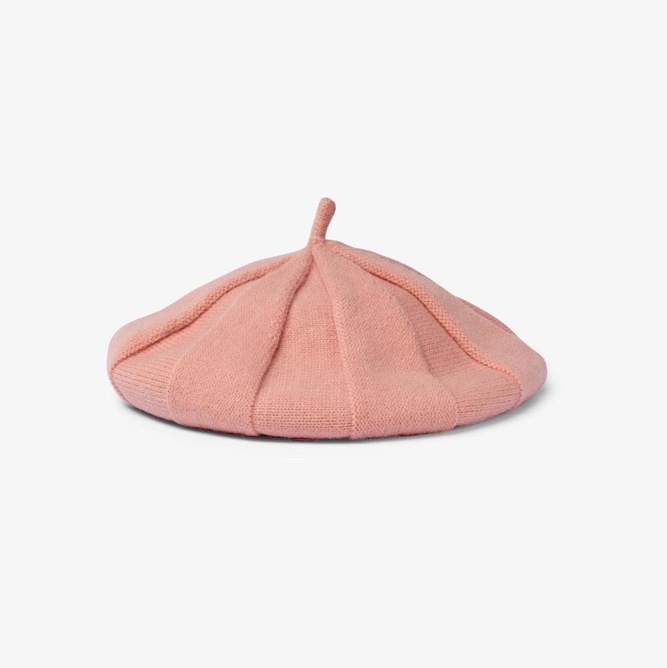Eine weiche Strick-Baskenmütze in einem sanften Rosé-Ton. Sichtbare Stricksegmente verleihen der Mütze Form und Volumen, minimalistisch präsentiert auf weißem Hintergrund.