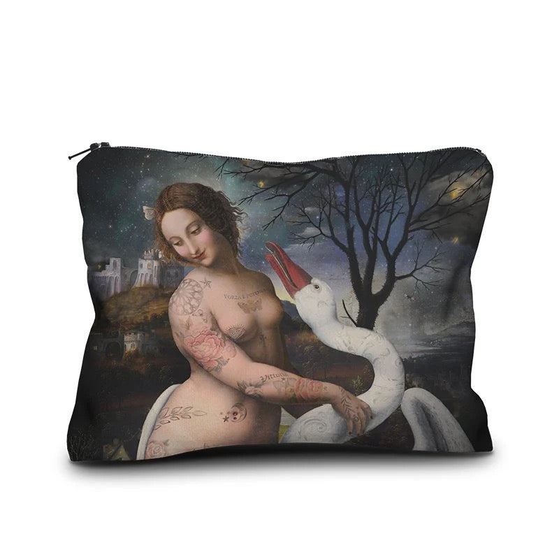 Eine rechteckige Kosmetiktasche mit Reißverschluss, bedruckt mit einer modernen, surrealistischen Interpretation des klassischen Kunstmotivs „Leda mit dem Schwan“. Im Zentrum steht eine lächelnde Frau mit Tätowierungen auf Armen, Schultern und Oberkörper, die einen großen weißen Schwan umarmt. Der Schwan hat seinen Schnabel weit geöffnet. Der Hintergrund zeigt eine nächtliche Landschaft mit einem kahlen Baum unter einem sternenklaren Himmel sowie eine Burg auf einem Hügel im Hintergrund.