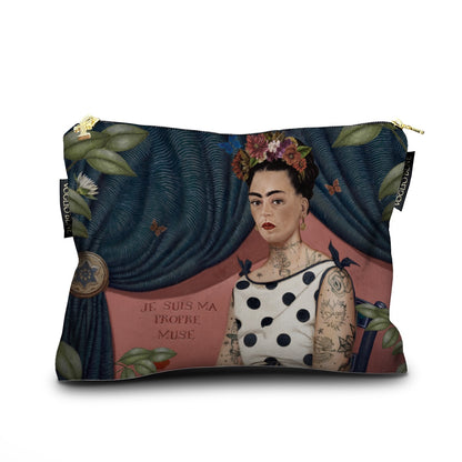 Eine gemusterte Stoff-Kosmetiktasche mit einem künstlerischen Porträt einer Frau, die an Frida Kahlo erinnert. Sie trägt ein gepunktetes Oberteil, Tätowierungen auf den Armen und bunten Blumenschmuck im Haar. Im Hintergrund ist ein schwerer, dunkelblauer Vorhang drapiert und links unten steht der Schriftzug „JE SUIS MA PROPRE MUSE“. Die Tasche hat einen goldenen Reißverschluss und zwei schwarze Logo-Etiketten.