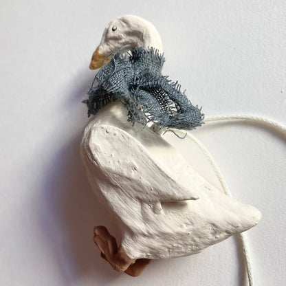 Seitenansicht der modellierten Gans mit fransigem blauen Schal und feiner Gefiederstruktur.
