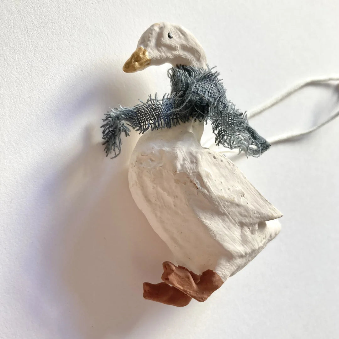 Seitenansicht der modellierten Gans mit fransigem blauen Schal und feiner Gefiederstruktur.