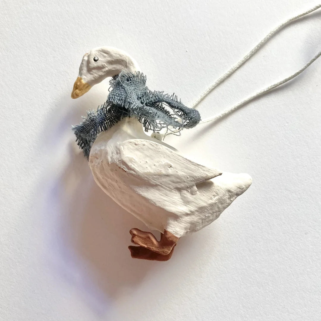 Seitenansicht der modellierten Gans mit fransigem blauen Schal und feiner Gefiederstruktur.