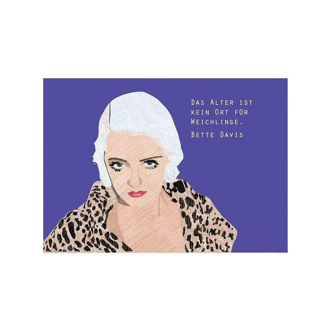 Eine Postkarte im Querformat auf strukturierter, naturfarbener Pappe. Auf der linken Seite ist ein Porträt der Schauspielerin Bette Davis mit hellen Haaren und einem Mantel im Leoparden-Muster vor einem blauen Hintergrund abgebildet. Rechts daneben steht das Zitat: „Das Alter ist kein Ort für Weichlinge.“ Darunter ist ihr Name „Bette Davis“ vermerkt.